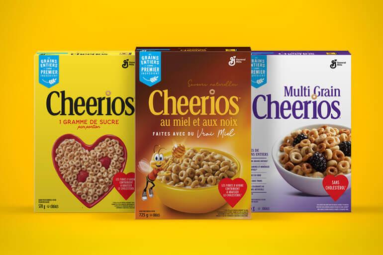 Une photo de famille de la face avant des Cheerios Original, Honey Nut Cheerios et Multi-grain Cheerios, sur un fond jaune.