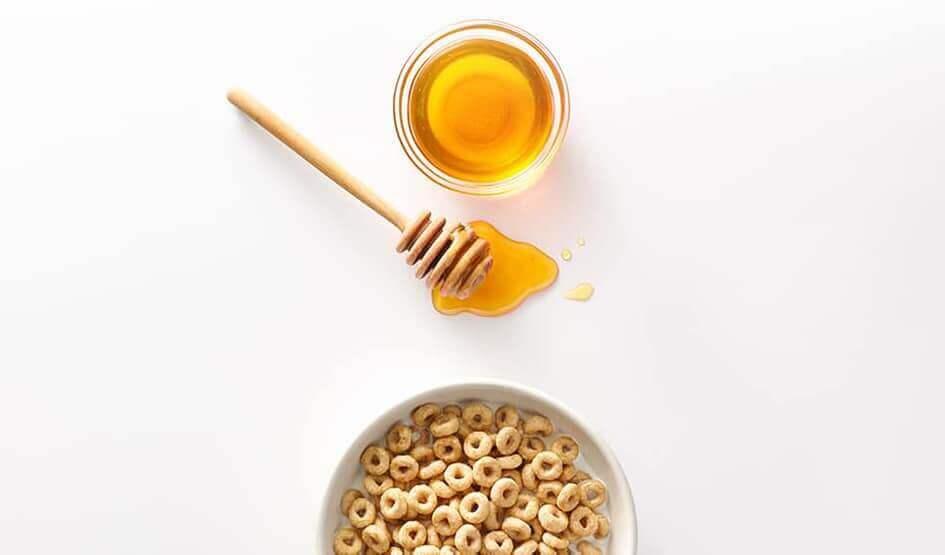 Du miel frais à côté d'un bol de Cheerios
